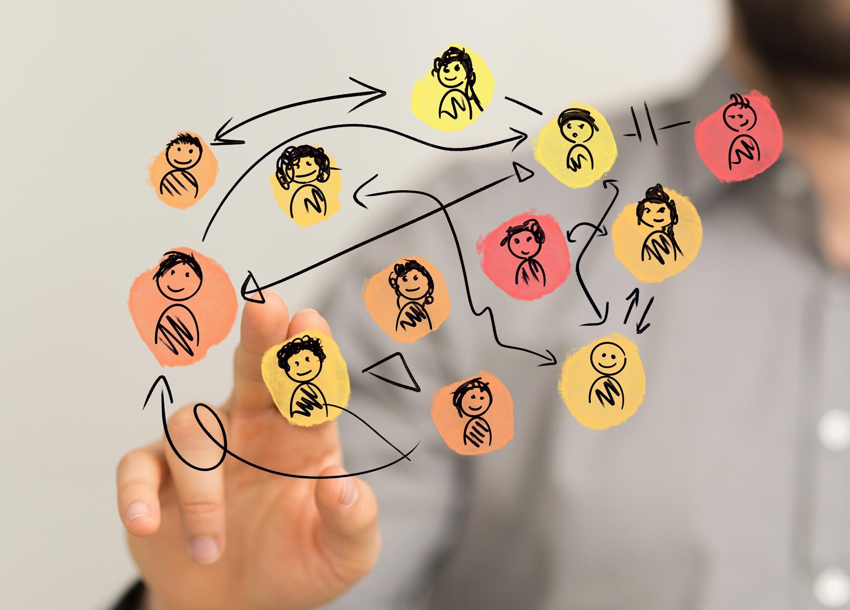 Ein Mann in grauem Hemd tippt auf eine transparente Oberfläche, auf der ein Netzwerk aus gezeichneten bunten Kreisen mit Strichmännchen und Verbindungspfeilen zu sehen ist – symbolisch für Kommunikation, Teamarbeit oder soziale Netzwerke.